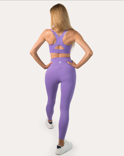 Full-length back view of purple sports bra showing racerback straps and longline band in stride
