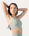 Sage green running sports bra in three-quarter front pose with arm raised