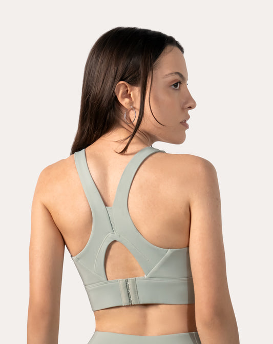 Sage green racerback running sports bra, back close-up showing keyhole and hook-back closure.