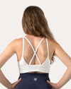 Back view of white backless sports bra highlighting crisscross straps and open back