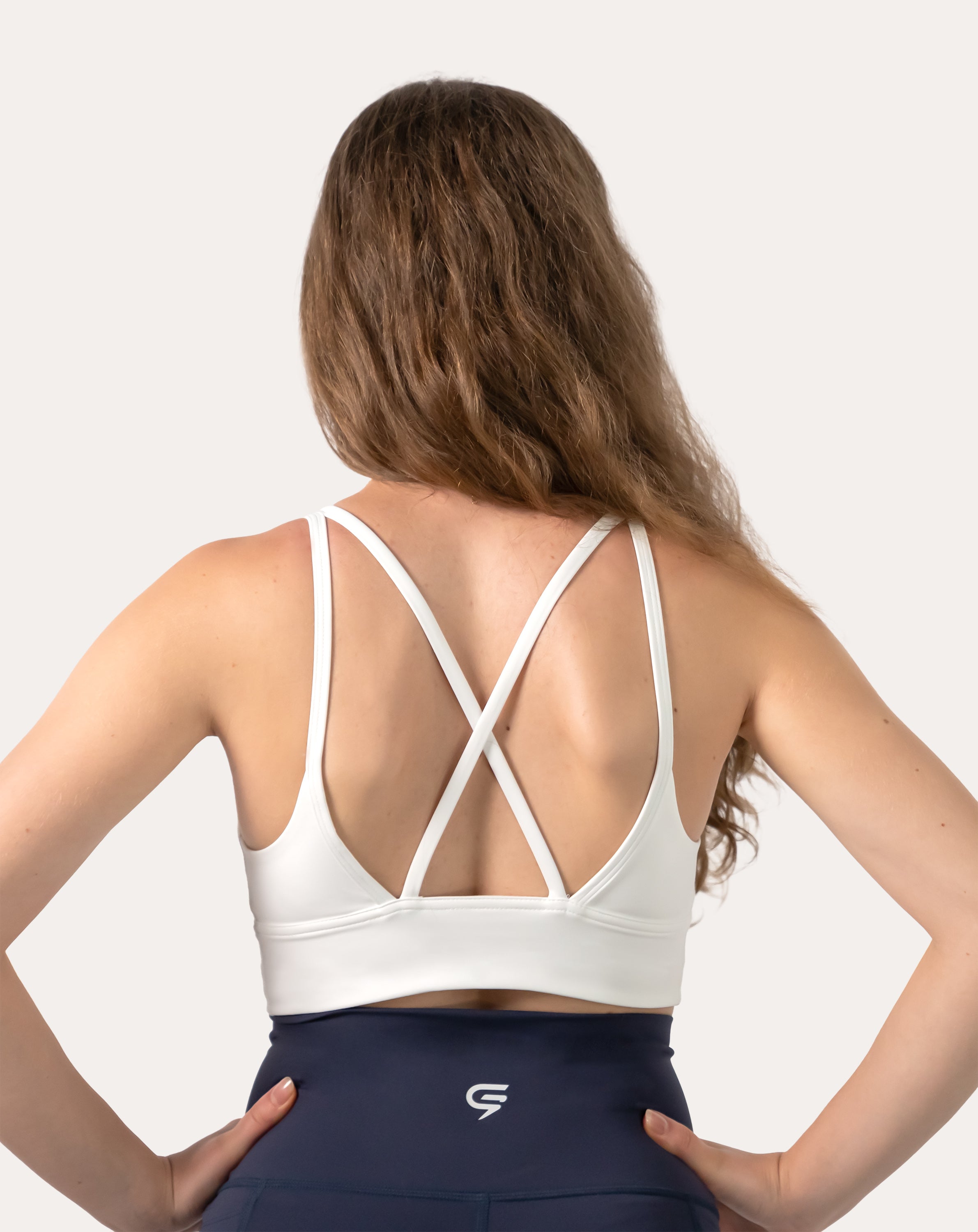 Back view of white backless sports bra highlighting crisscross straps and open back