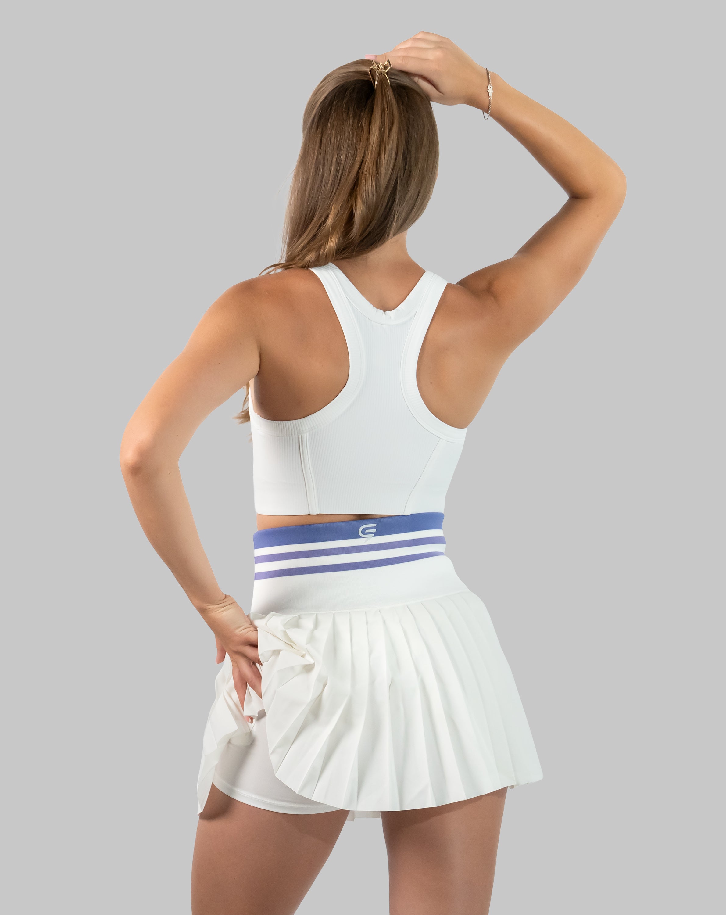 Full-body back view of white pleated golf skirt with striped high-waist band