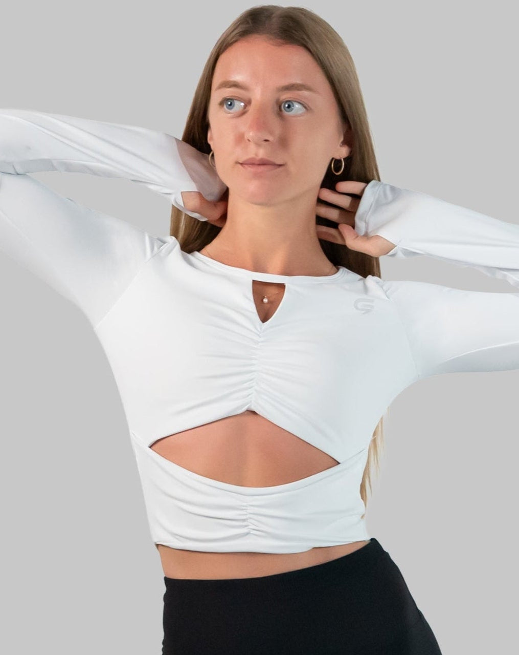 White gym top front close-up with arms raised; ruched center, front cut-out and sleeve thumbholes