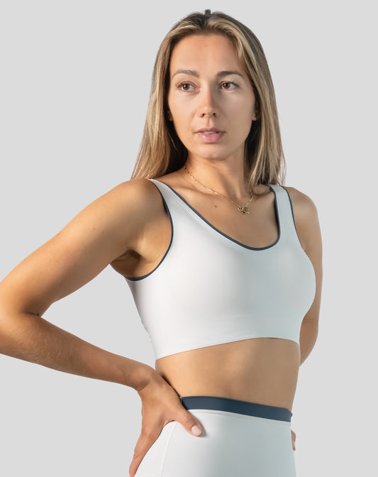 White seamless sports bra with contrast trim, three-quarter front close-up showing scoop front and band
