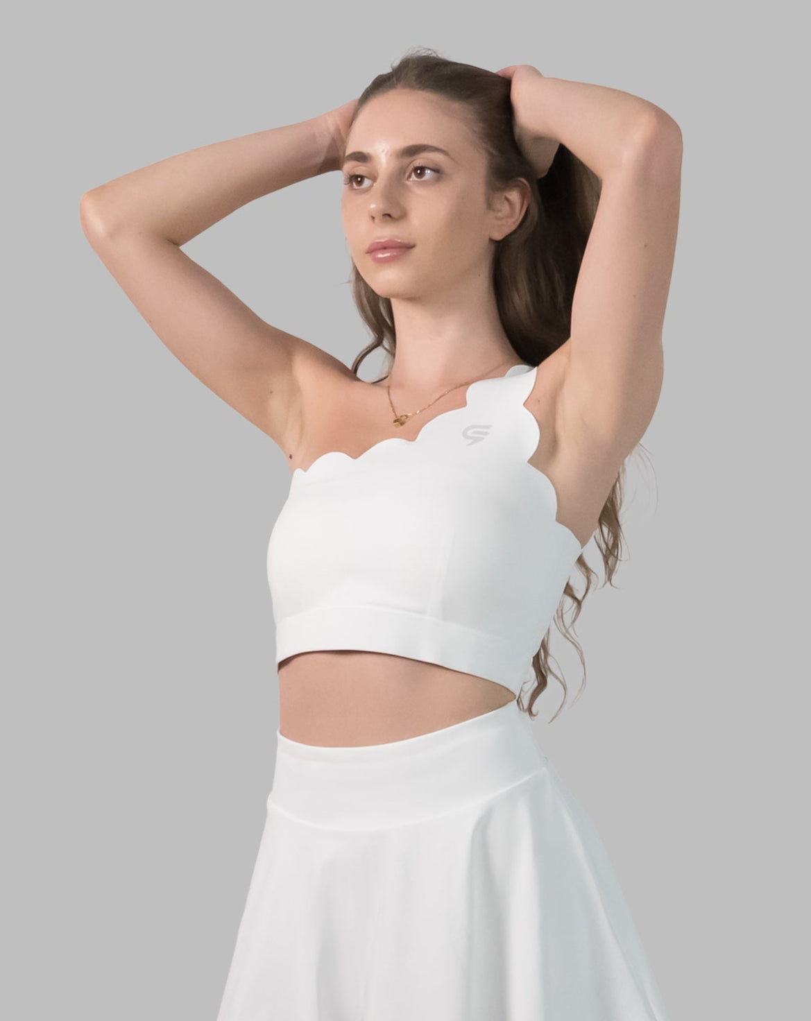 Front view of white sports bra with arms raised to show fit, support and cropped length