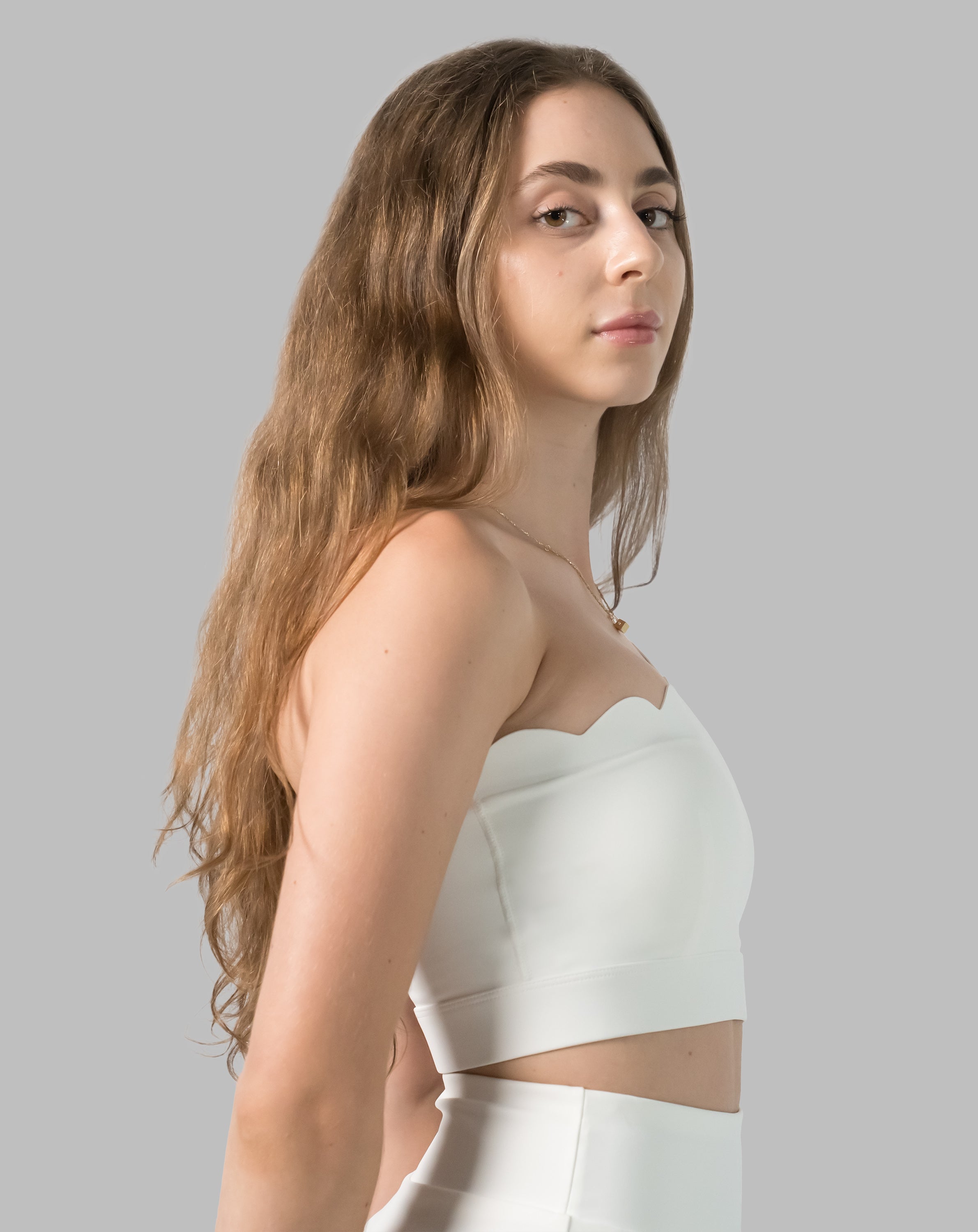 Right three-quarter view highlighting the scalloped neckline on the white sports bra