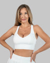 Front view of white strappy back sports bra with hands on hips; V-neck and supportive band