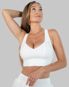 White strappy back sports bra, three-quarter front with arm raised; V-neck and wide underband