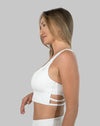 Side profile of white strappy back sports bra showing wide straps and supportive underband