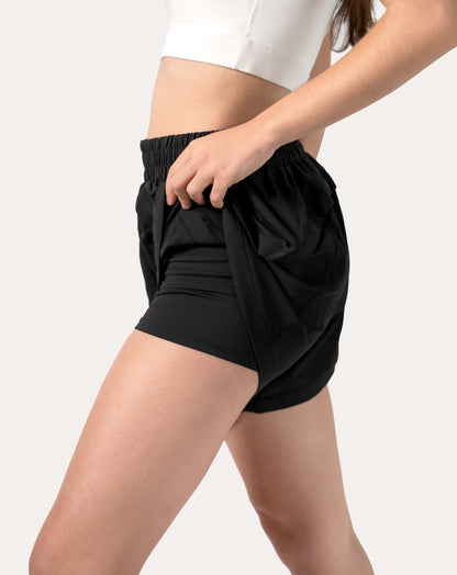 Front left three-quarter view of black women's 2-in-1 running shorts with curved split hem