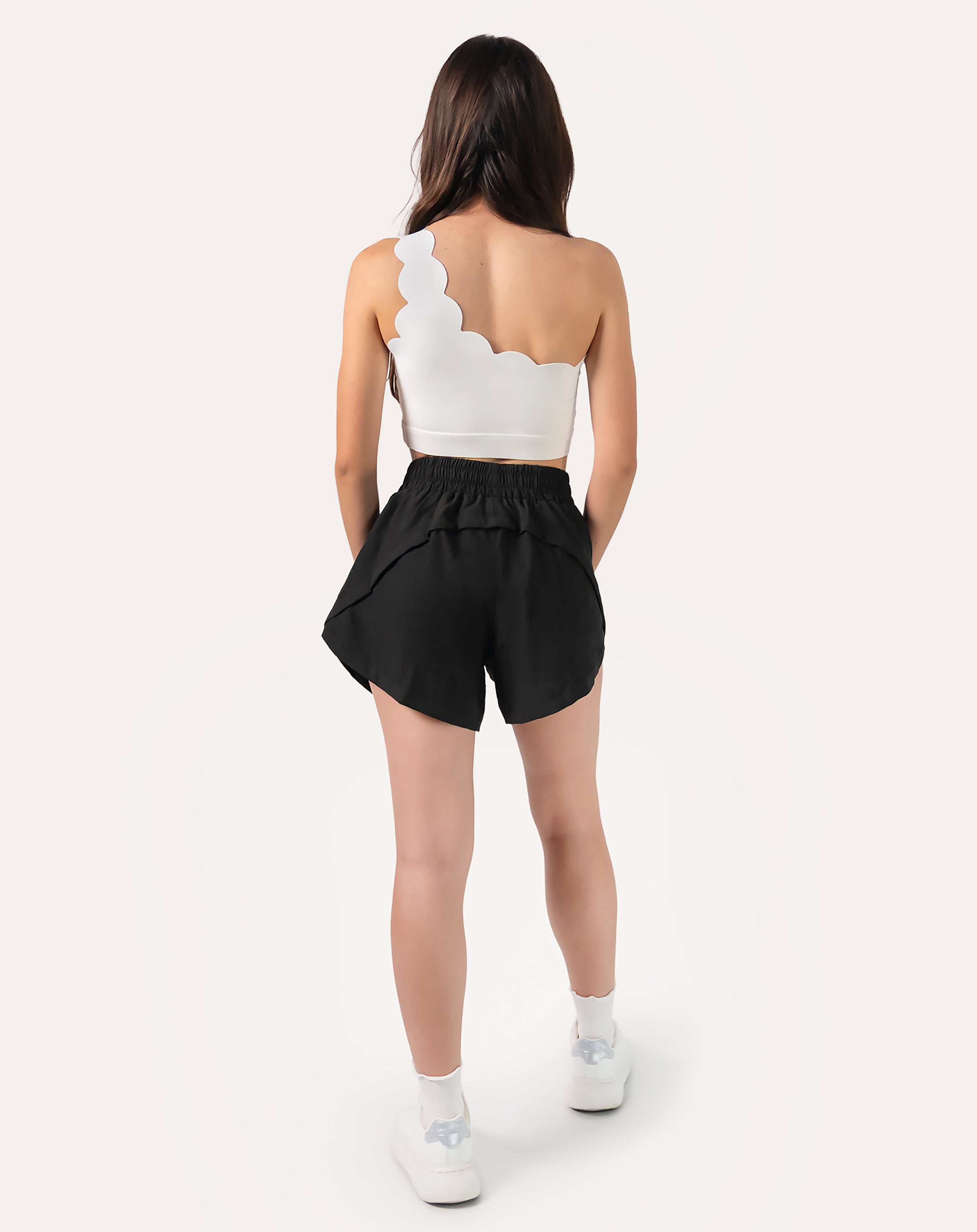 Full-body back view of black women's 2-in-1 running shorts with elastic waistband and split hem