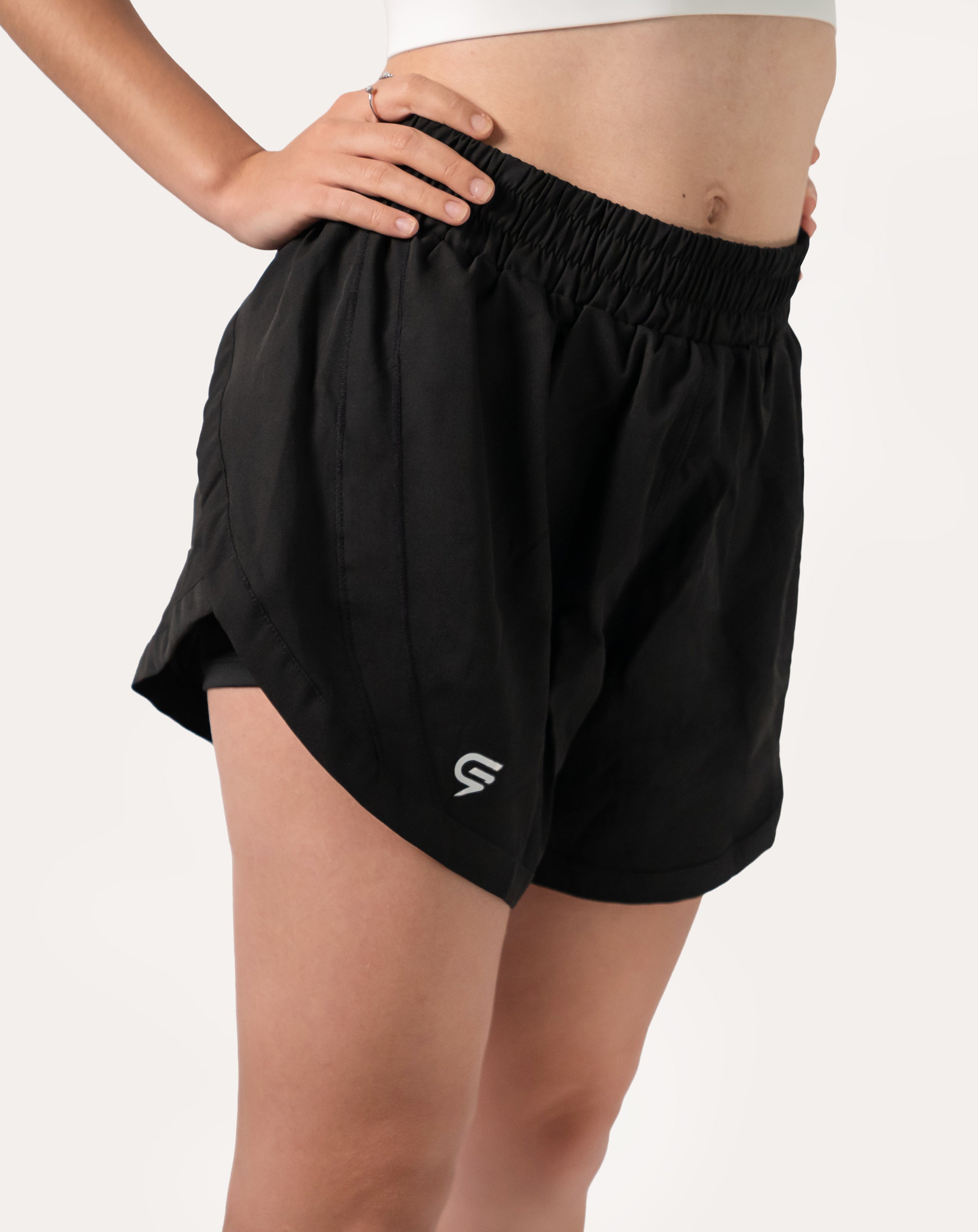 Right side close-up of black women's 2-in-1 running shorts highlighting curved split hem.