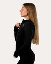 Women’s black gym jacket, right-side profile highlighting the slim fit sleeves and thumbholes