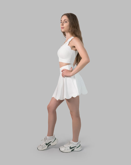 Women’s gym skirt set in white, side view with one-shoulder crop and flared skirt