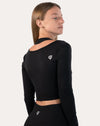 Back three-quarter view of black long sleeve gym top womens showing cropped fit and raglan sleeves.