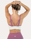 Back view of white/lilac women’s sports bra with strappy open back; arms raised