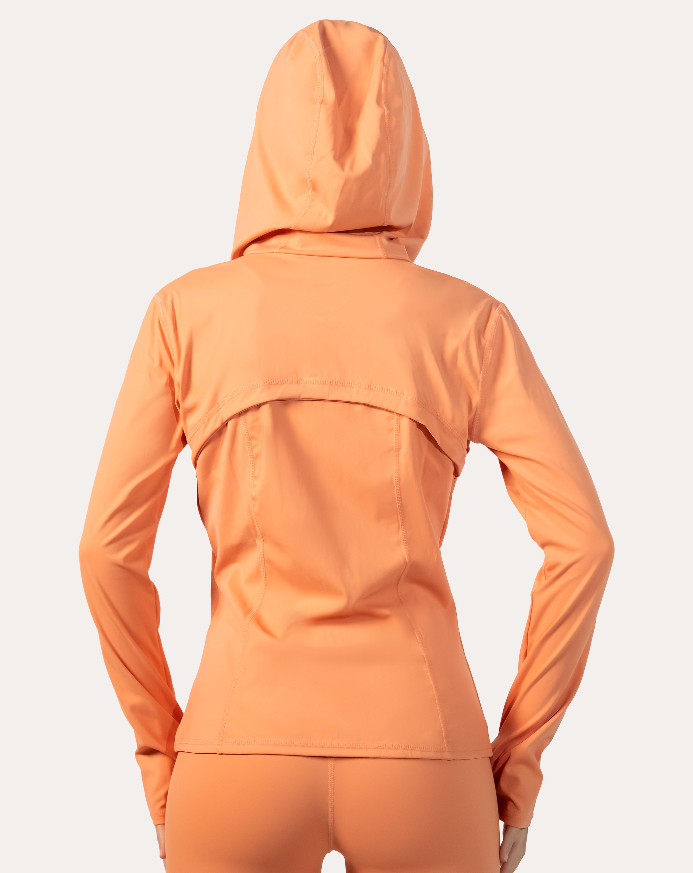 Apricot women’s zip-up jacket, back view with hood down and streamlined hem