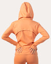 Back view of apricot women’s zip-up jacket with hood up and vented back yoke