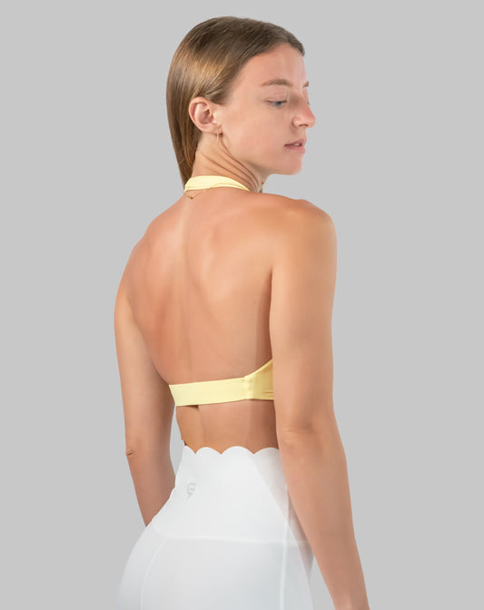 Back view of yellow halter neck sports bra highlighting open back and supportive underband