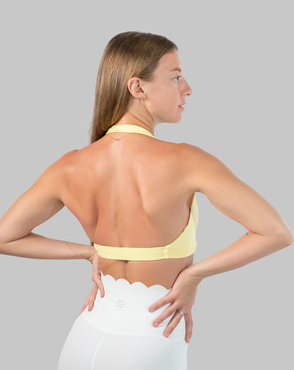 Yellow halter neck sports bra, three-quarter back view with open back and halter strap