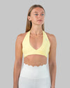 Front view of yellow halter neck sports bra with wrap V-neck and smooth finish