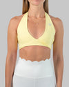 Yellow halter neck sports bra, close-up showing wrap V-neck and wide underband.