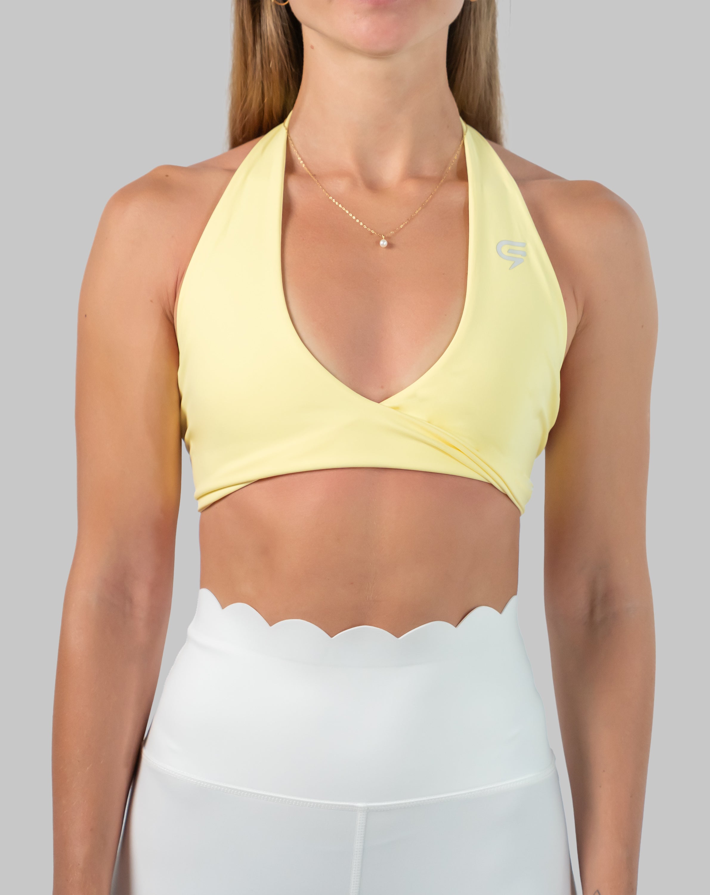 Yellow halter neck sports bra, close-up showing wrap V-neck and wide underband.