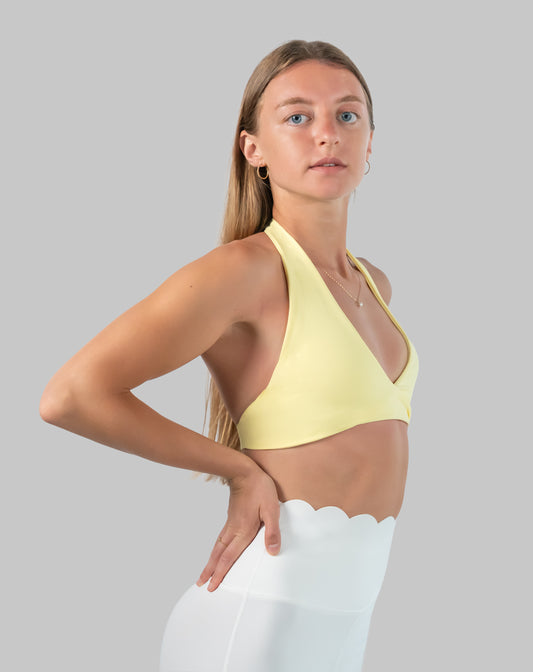 Yellow halter neck sports bra with wrap V-neck, front three-quarter view