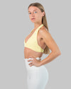 Yellow halter neck sports bra in three-quarter front pose with soft halter strap