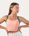 Side profile of peach and green yoga sports bra with wide green straps and longline hold.