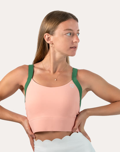Side profile of peach and green yoga sports bra with wide green straps and longline hold.
